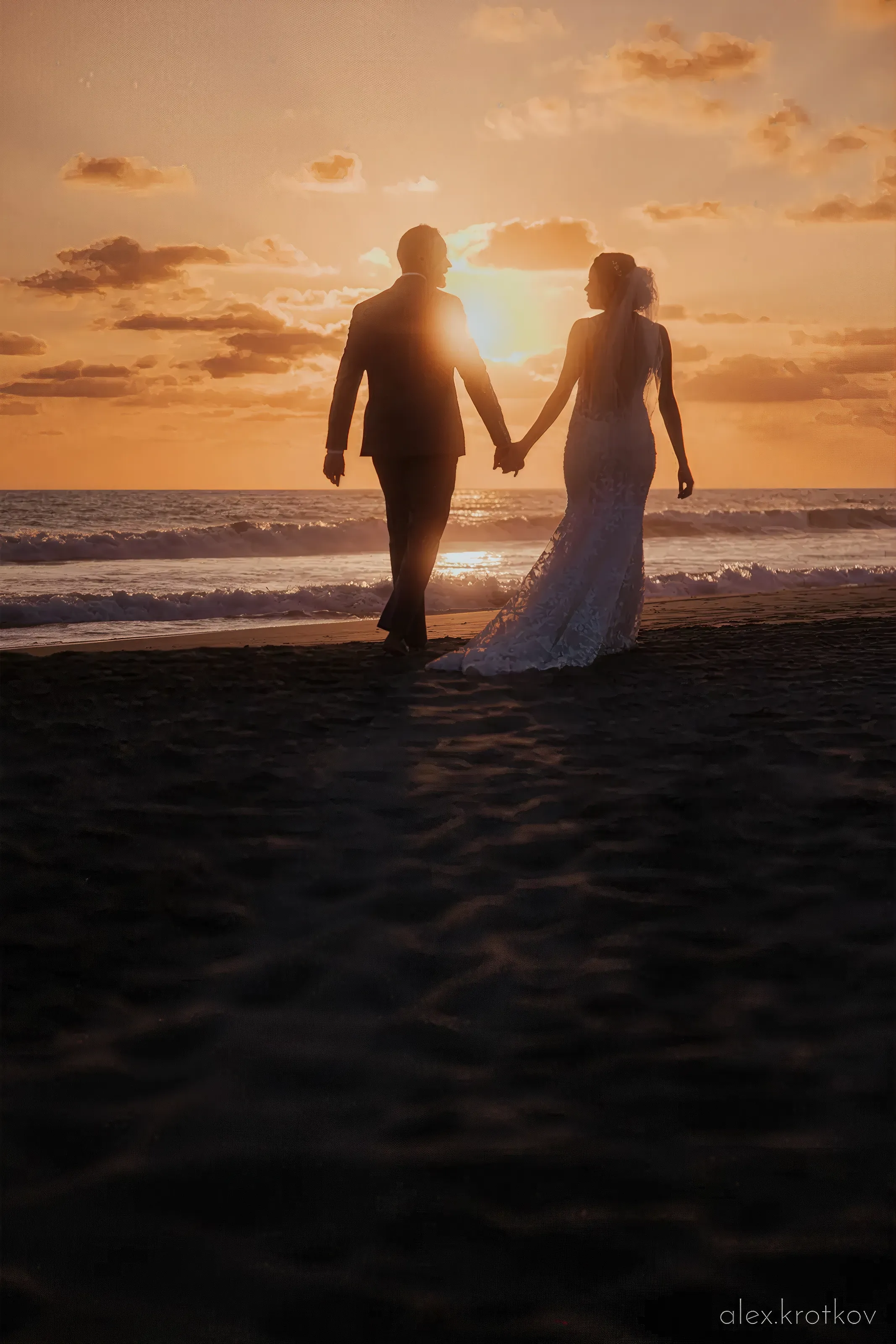 Married couple hold hands face to a sunset